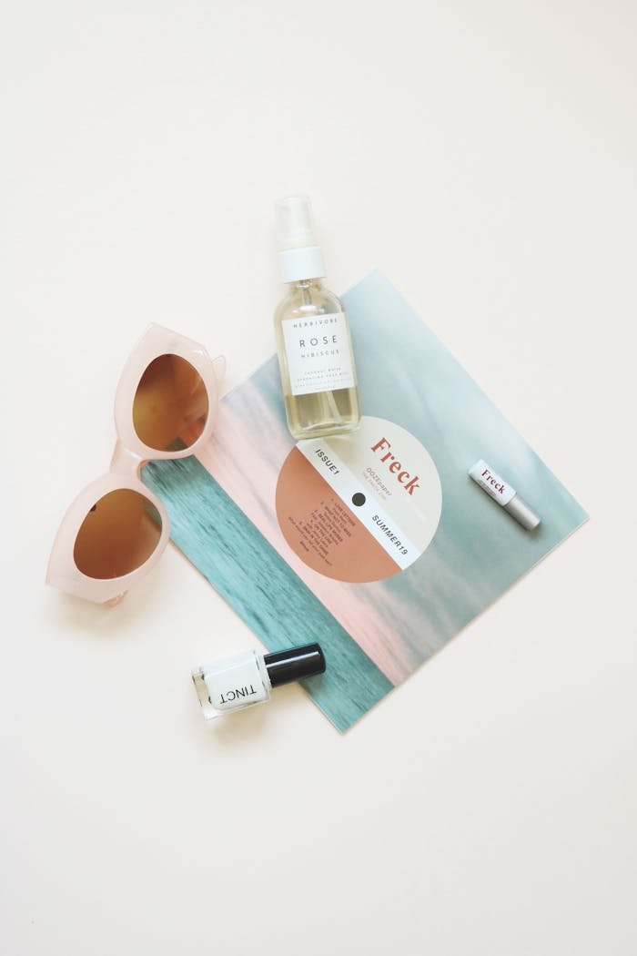 High-angle flatlay of summer essentials including sunglasses and skincare products.