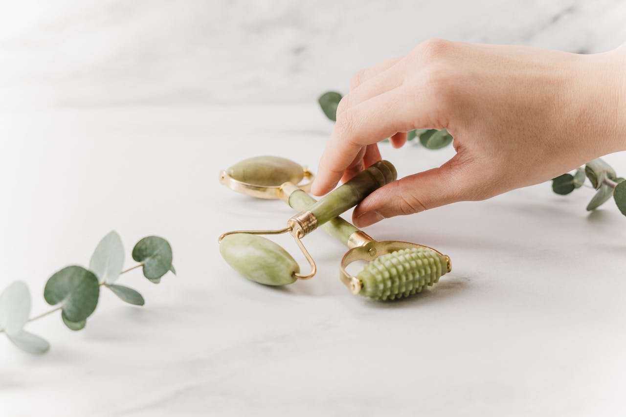 why-choose-us-img Close-up of a hand holding jade rollers on a marble surface for skincare and wellness.